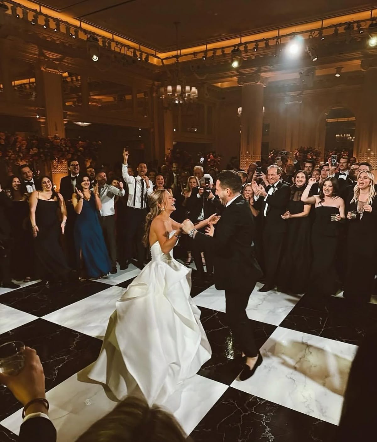 Aerial view of a couple dancing on a checkerboard dance floor surrounded by cheering guests in Tulsa