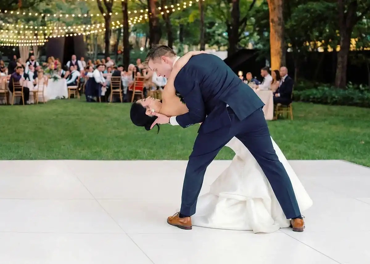Bride and groom holding hands on a black and white checkerboard dance floor at a Tulsa wedding reception