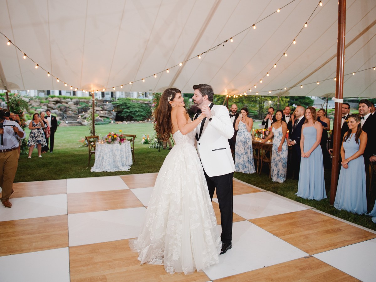 Aerial view of a checkerboard dance floor with bridesmaids lined up beside a floral sweetheart table in Tulsa