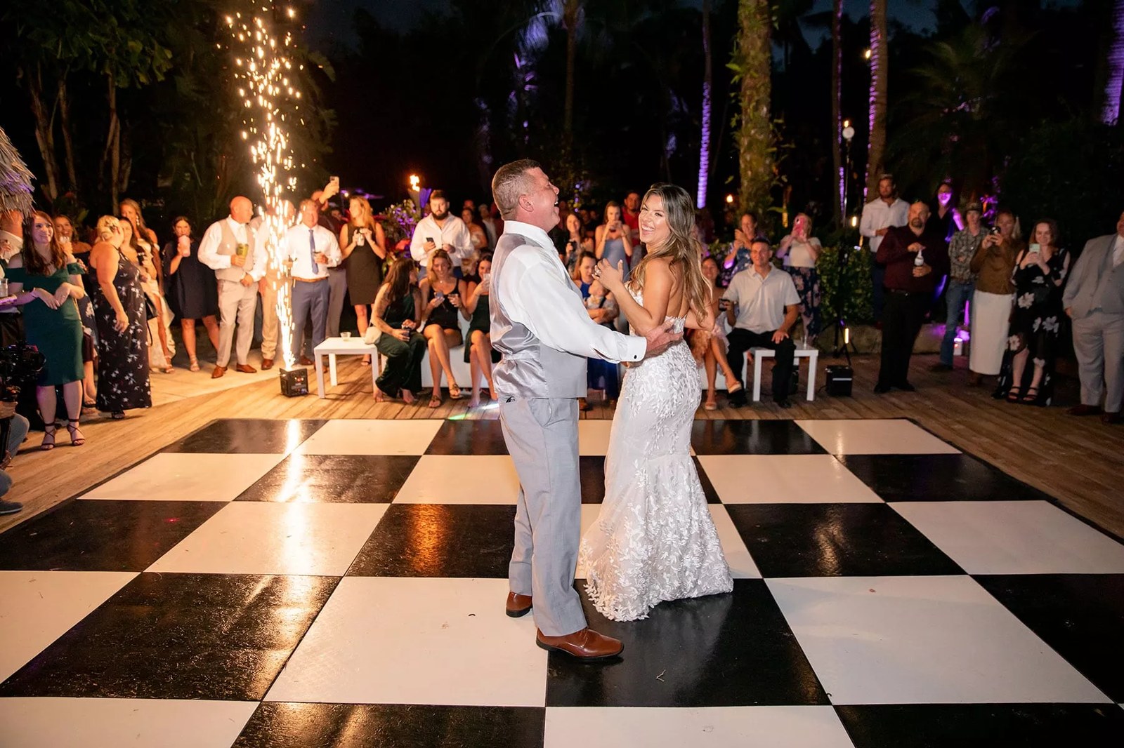 Groom lifting his bride on a checkerboard dance floor at an industrial style Tulsa wedding venue