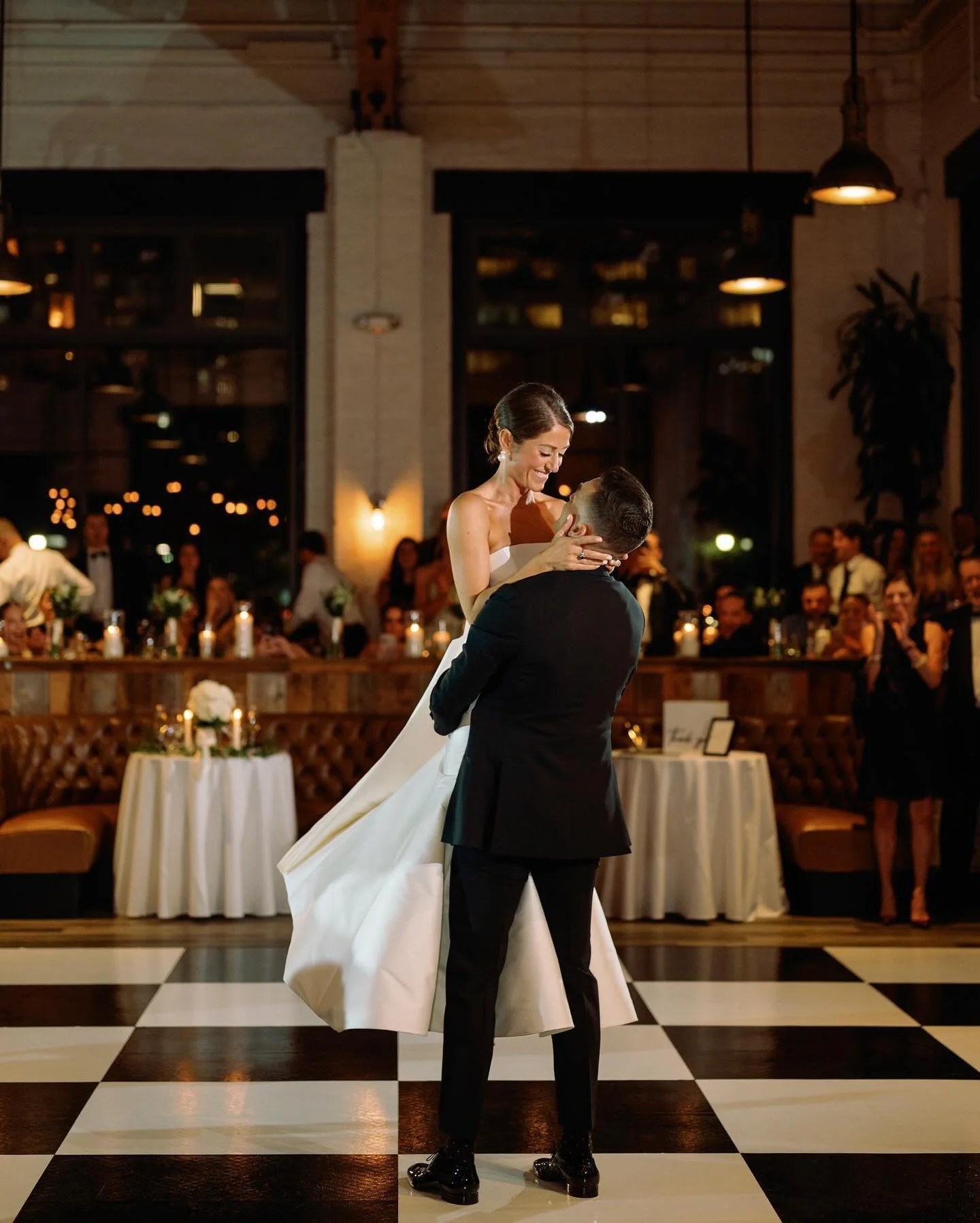 Newlyweds beginning their first dance on a checkerboard dance floor in a chandelier lit Tulsa ballroom